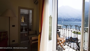Een balkon met uitzicht op een meer en bergen, een stoel en een lamp.