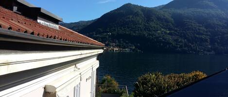 A building with a red-tiled roof overlooking a lake and mountains.