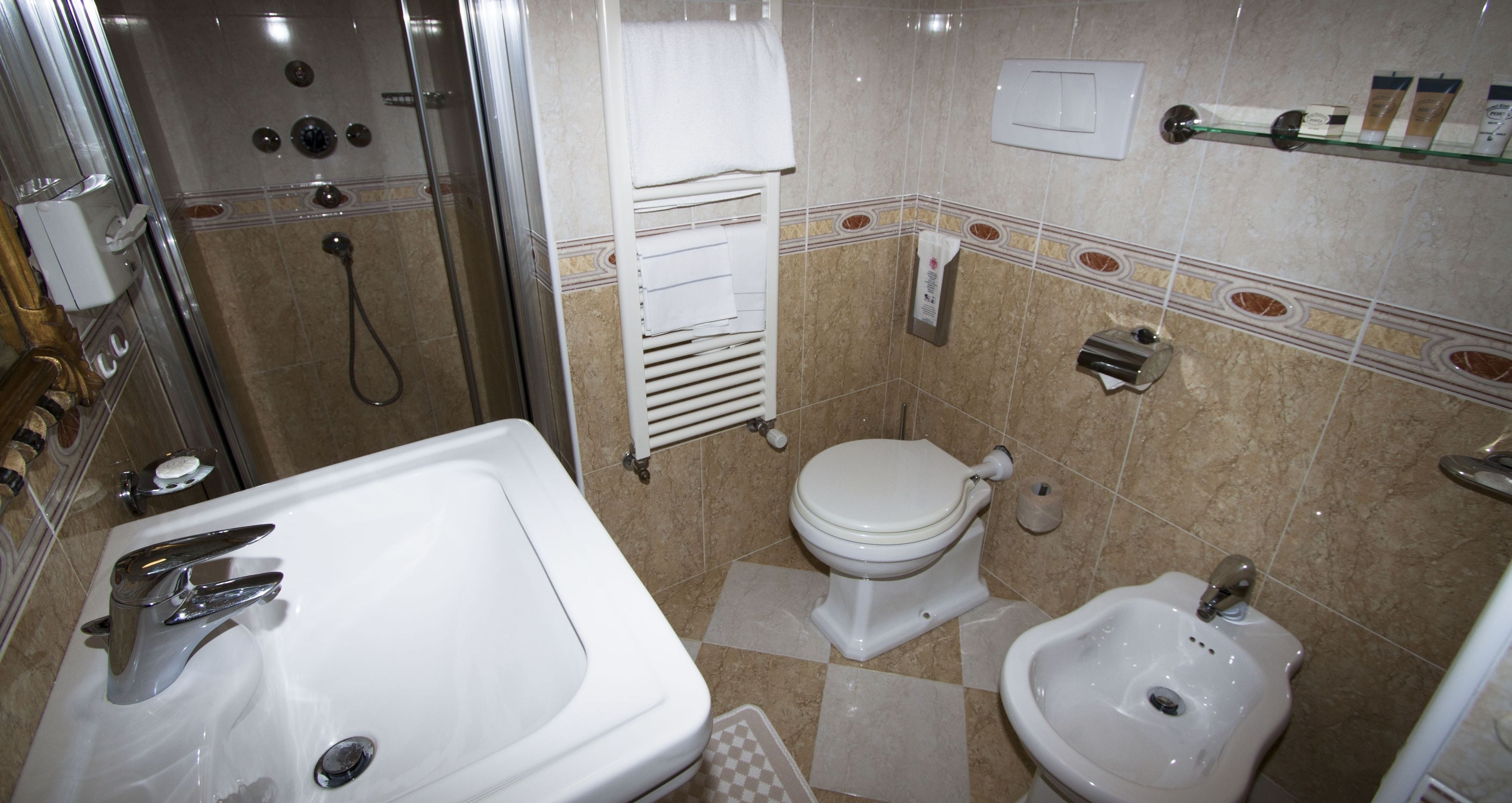 A bathroom with a shower, toilet, bidet, and sink.