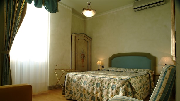 A bedroom with a bed, a chair, a dresser, and a lamp. - Hotel Posta (Moltrasio)