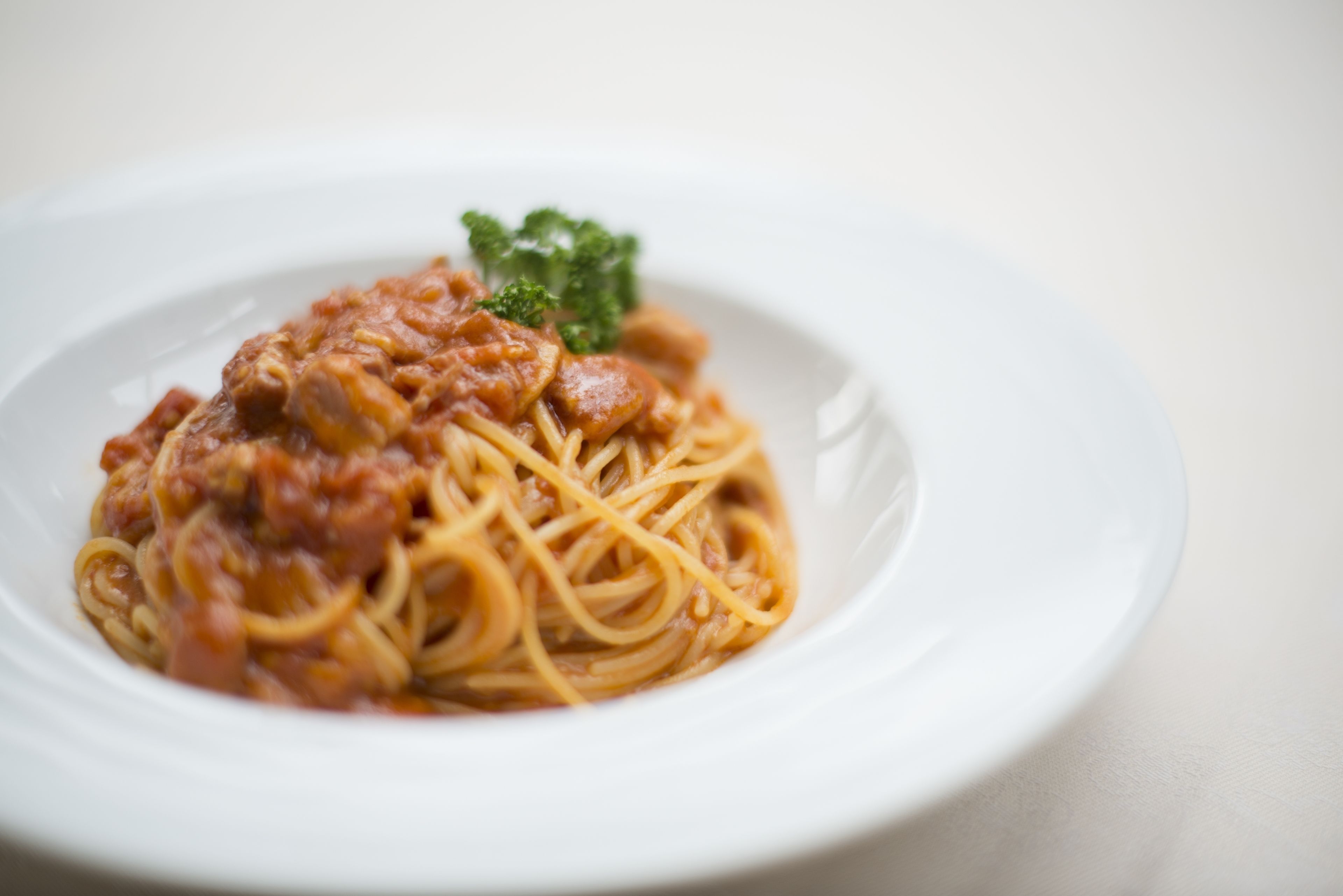 En tallrik spaghetti med tomatsås och en garnering.