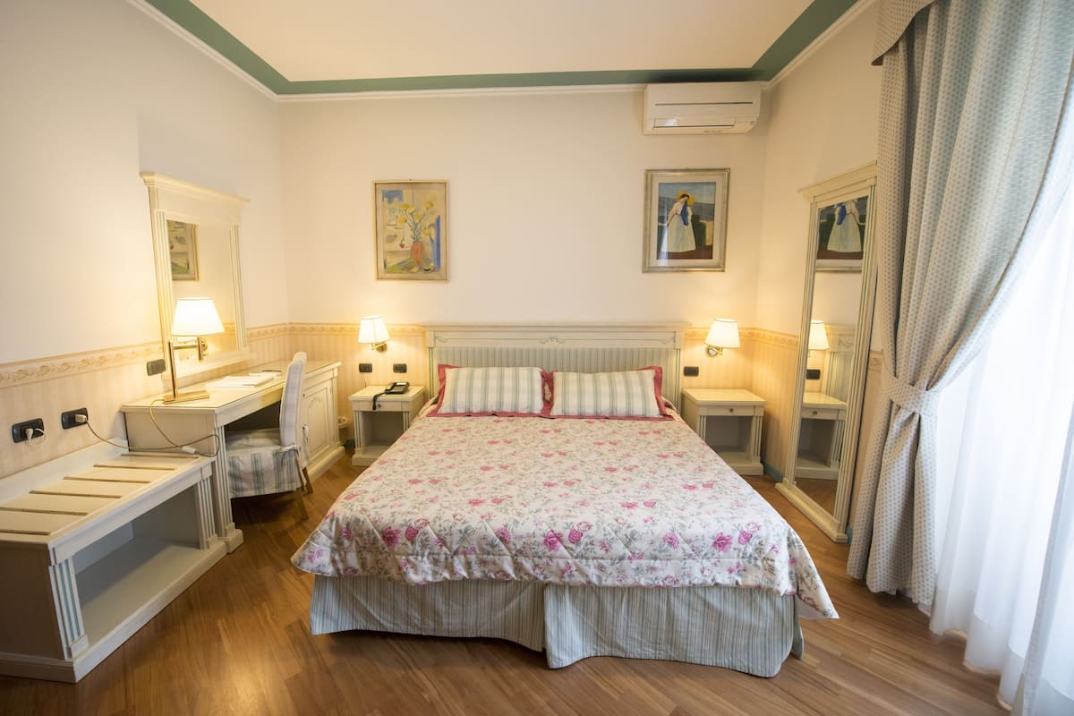 Ein Hotelzimmer mit Bett, Nachttischen, Schreibtisch und Stuhl.