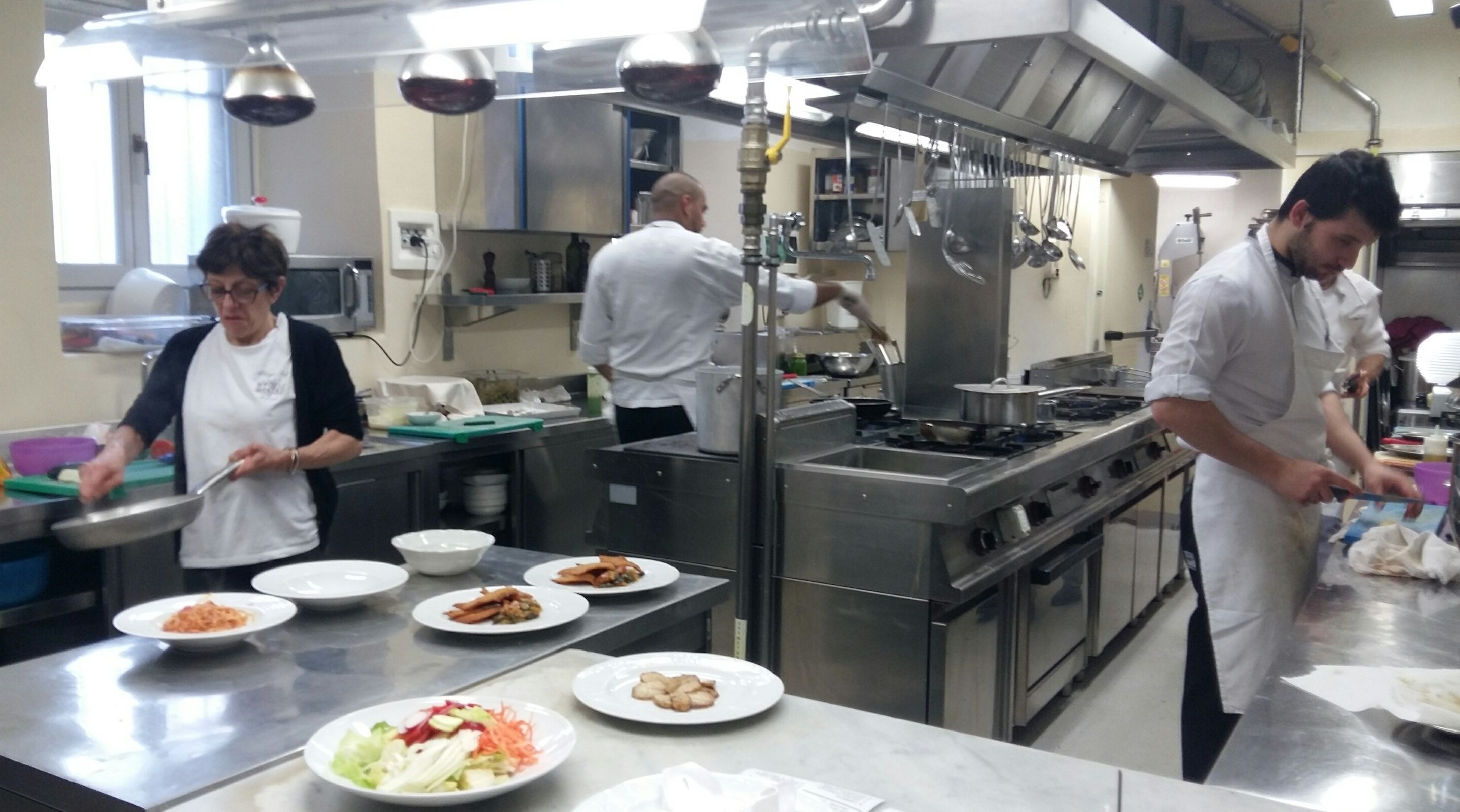 A commercial kitchen with stainless steel surfaces, various cooking equipment, and multiple chefs preparing dishes.