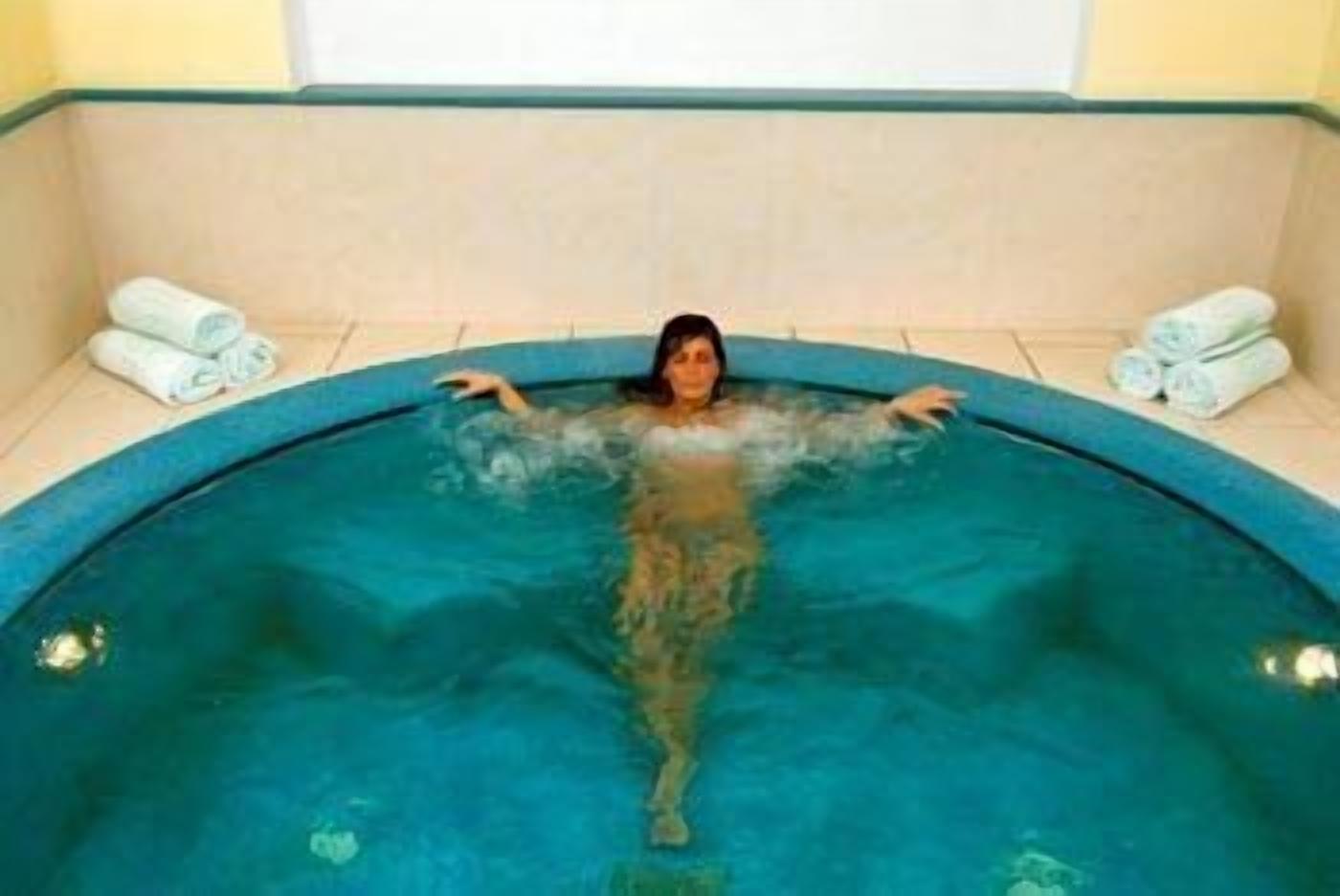 A person in a hot tub with towels on the sides.