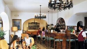 Un vestíbulo de hotel con zona de bar, arreglos de asientos y una araña.