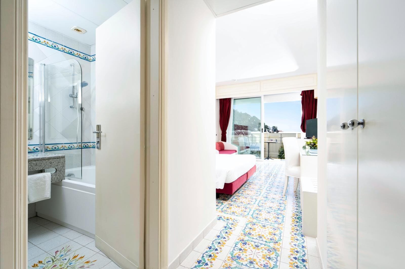 A hotel room with a bathroom, a shower, a bed, and a balcony with a view.