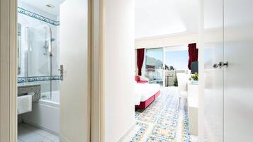 A hotel room with a bathroom, a shower, a bed, and a balcony with a view.