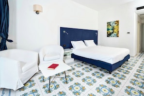 Una habitación de hotel con una cama, una silla, una mesita de noche y una lámpara de pared.