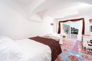 Habitación de hotel con cama, sofá, escritorio y un amplio ventanal con cortinas.