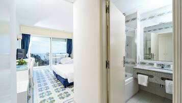 Hotelkamer met balkon, een bed, bureau met computer en badkamer met douche en wastafel.