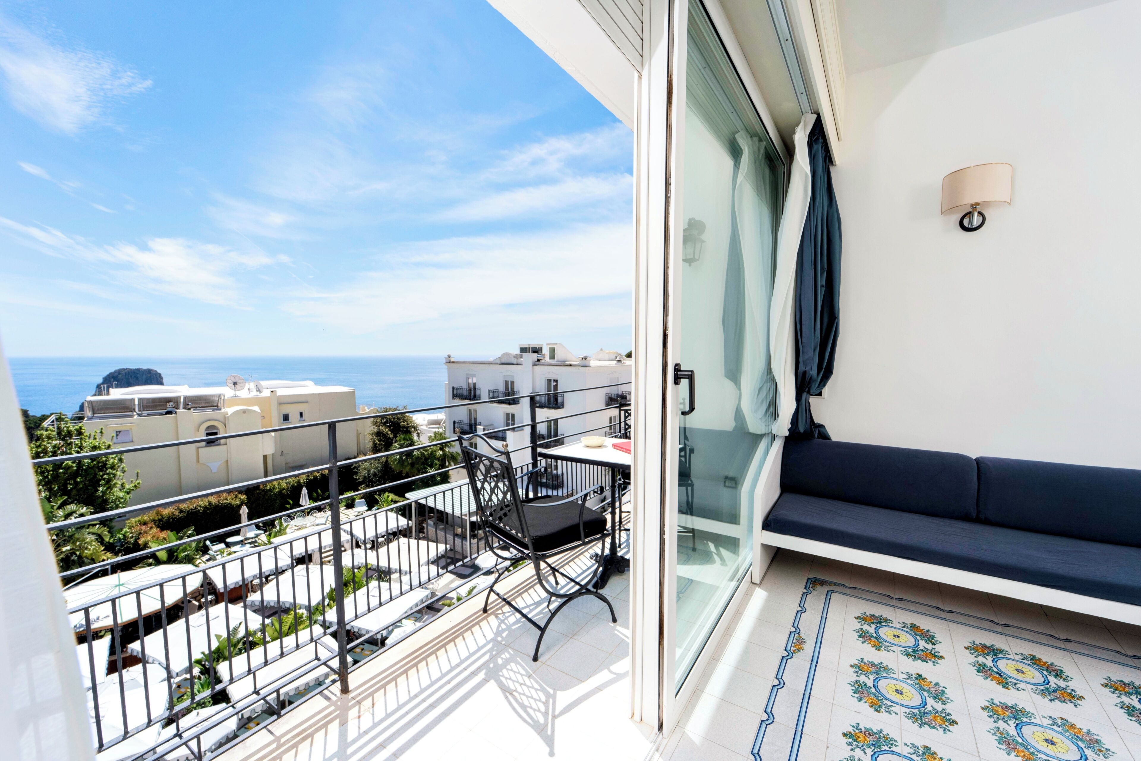 A balcony with a view of the sea, a sofa, and a dining table.