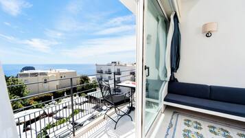 A balcony with a view of the sea, a sofa, and a dining table.