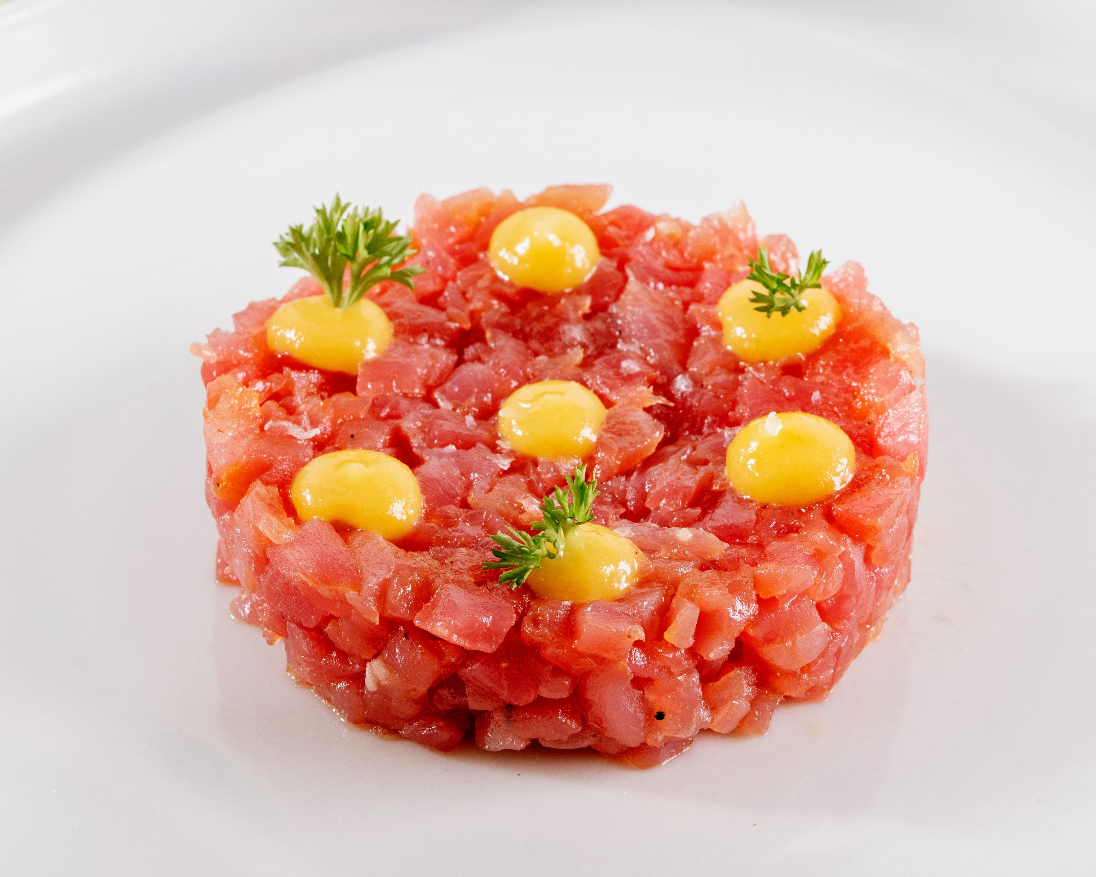 Un plat composé de viande crue finement hachée, disposée en cercle sur une assiette blanche.