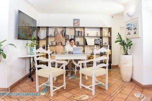 Una habitación con un escritorio blanco, dos sillas, una computadora portátil, una estantería y diversos objetos decorativos.
