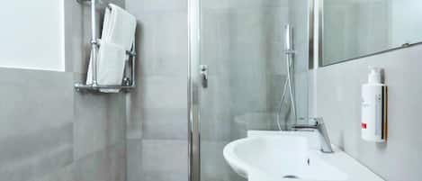 Un baño moderno con ducha de vidrio, lavamanos independiente y retrete.