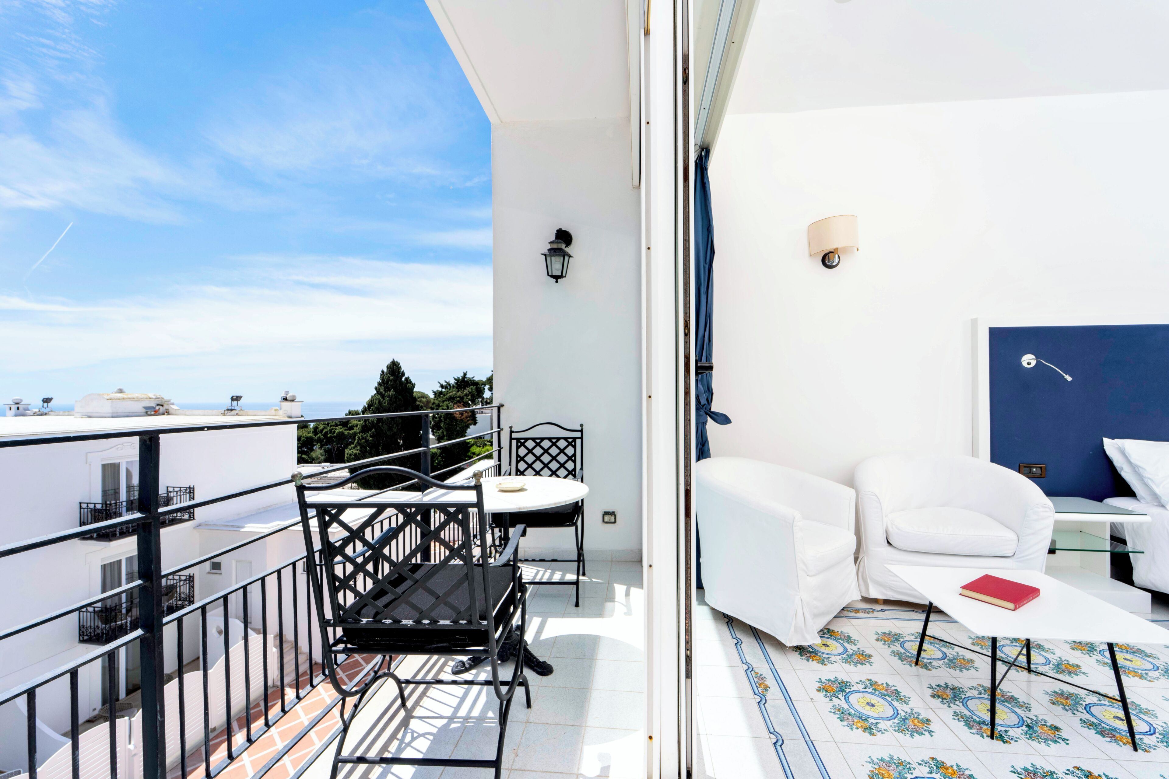 Een balkon met een tafel, stoelen, een bank en uitzicht op zee.