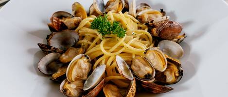 A plate of spaghetti with clams and parsley garnish.