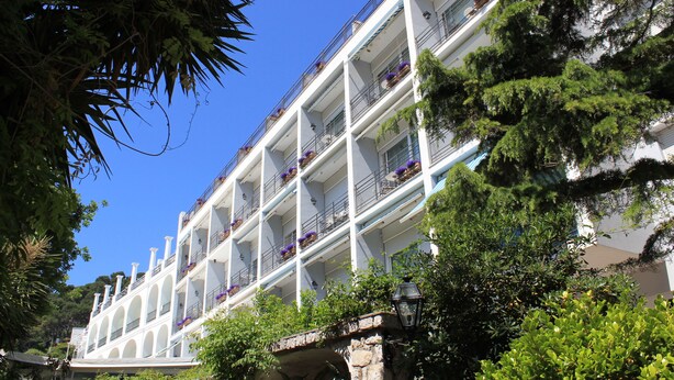 Un hotel de varios pisos con balcones, cada uno decorado con plantas en macetas.