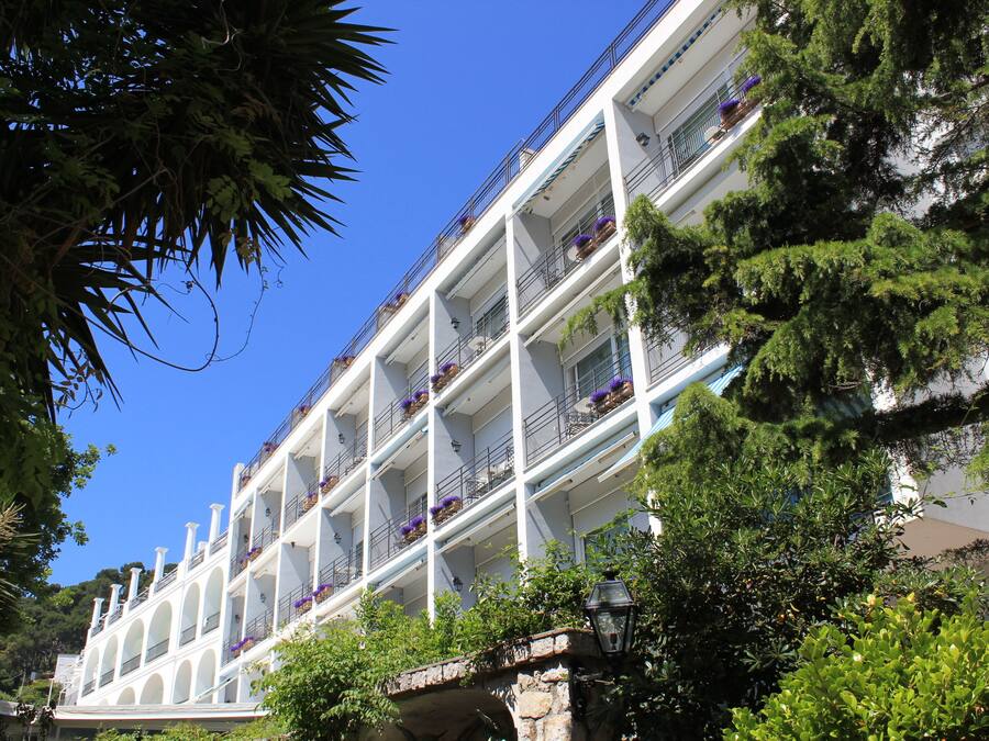 Een meerlaags hotel met balkons, elk versierd met potplanten.