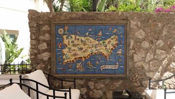 A stone wall with a tiled map of Italy, featuring various landmarks and sea creatures.