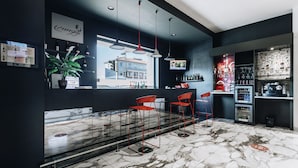 Un bar moderno con suelo de mármol, taburetes rojos y un amplio ventanal con vistas a un paisaje urbano.