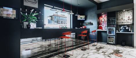 Un bar moderno con suelo de mármol, taburetes rojos y un amplio ventanal con vistas a un paisaje urbano.