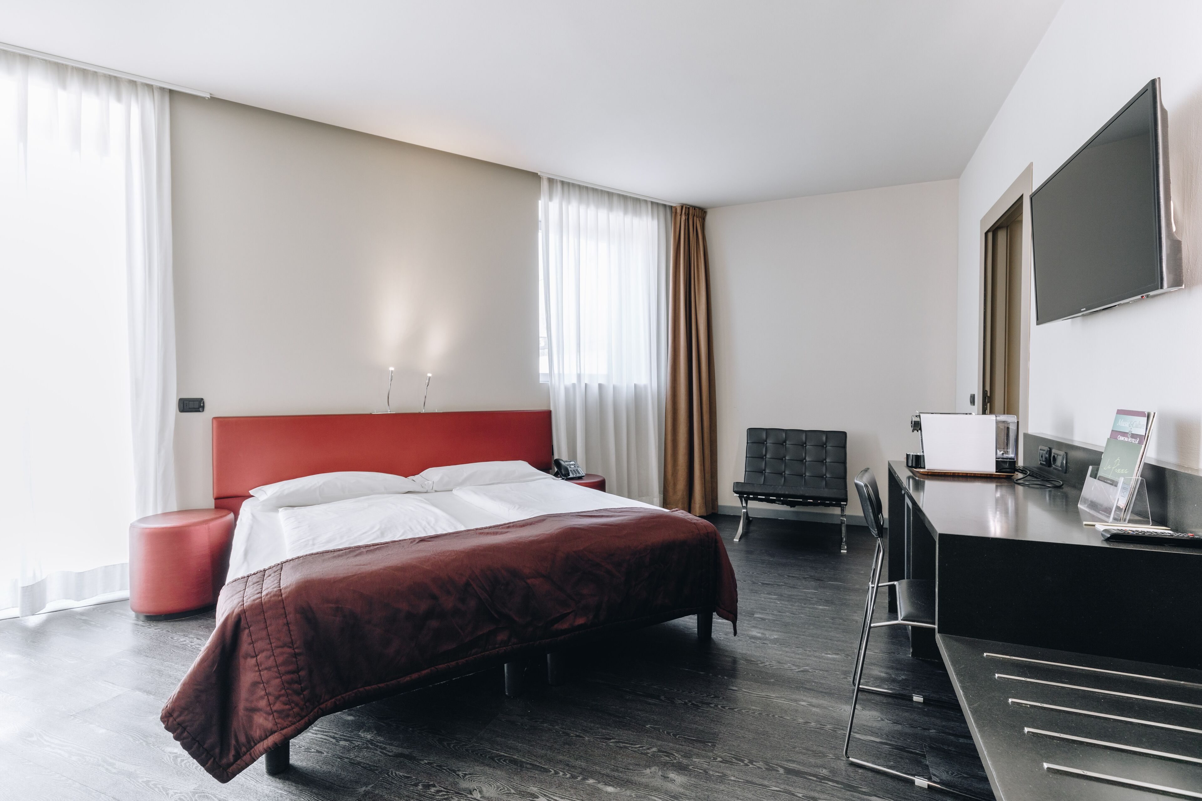 Una habitación de hotel moderna con una cama grande, un escritorio, una silla y un televisor de pantalla plana.