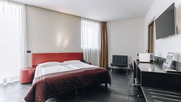 Una habitación de hotel moderna con una cama grande, un escritorio, una silla y un televisor de pantalla plana.