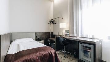 Habitació d'hotel amb llit, escriptori, cadira i un mini bar.