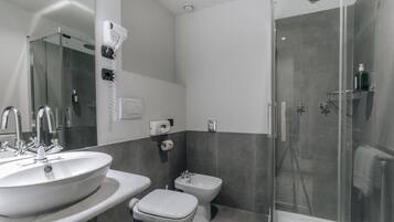 Et moderne badeværelse med en stor vask, en bidet og en brusekabine med glasvægge.