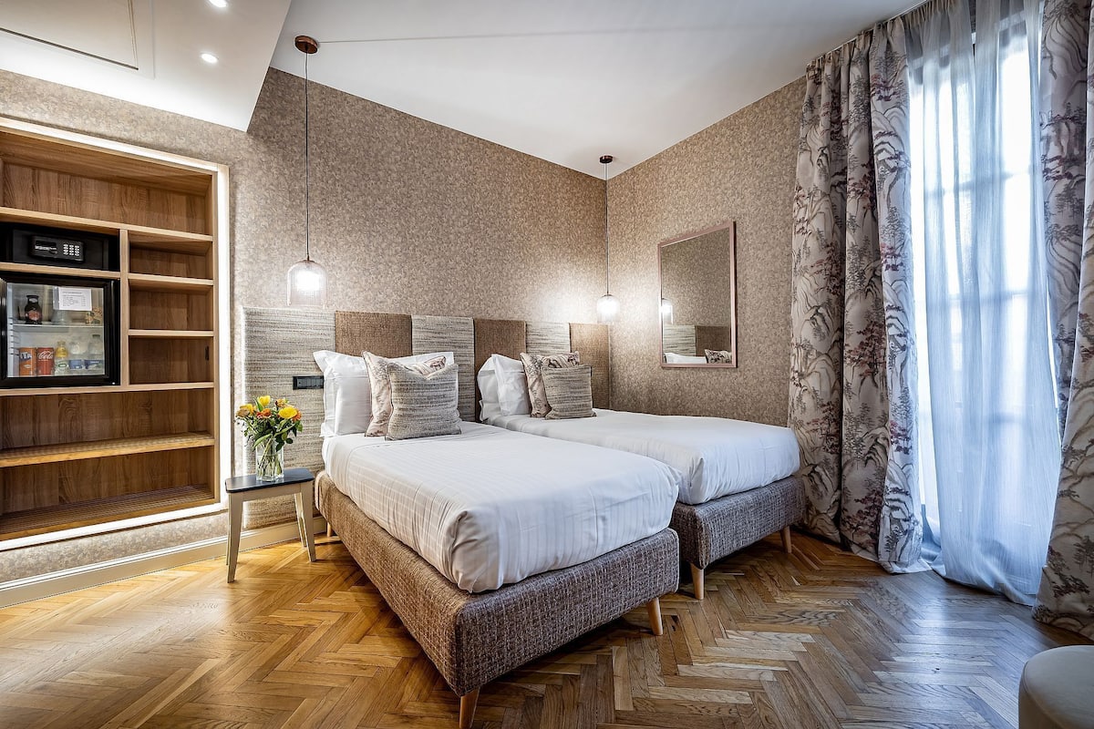 Un dormitorio moderno con dos camas, una estantería de madera y un espejo grande.