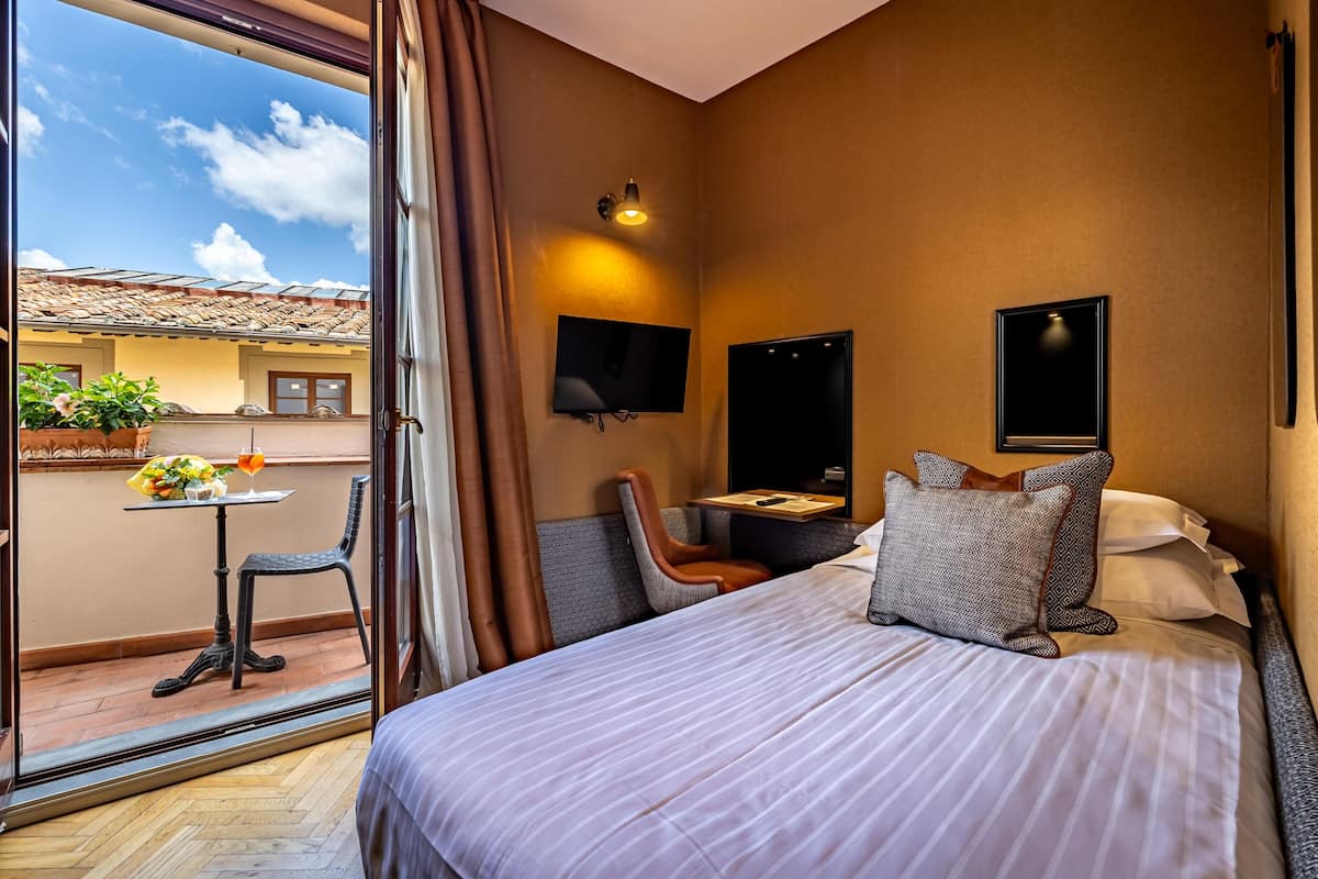 Habitación de hotel con cama, televisión, escritorio, silla y vistas al exterior.