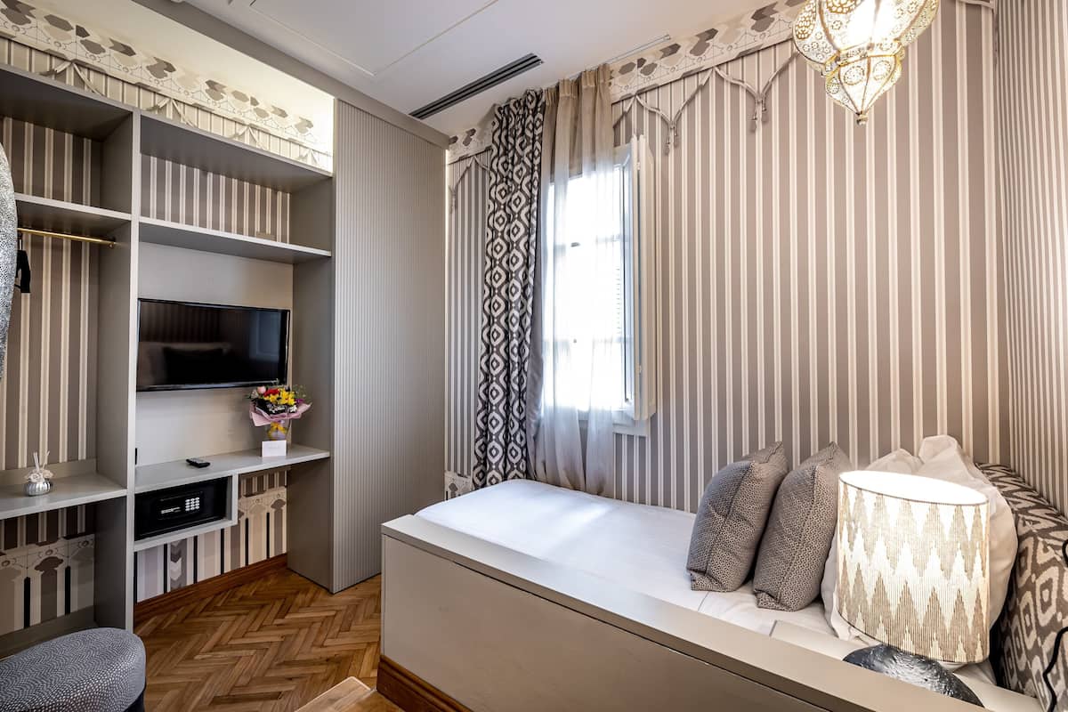 Un dormitorio moderno con una cama grande, televisor integrado, estanterías y una lámpara decorativa.