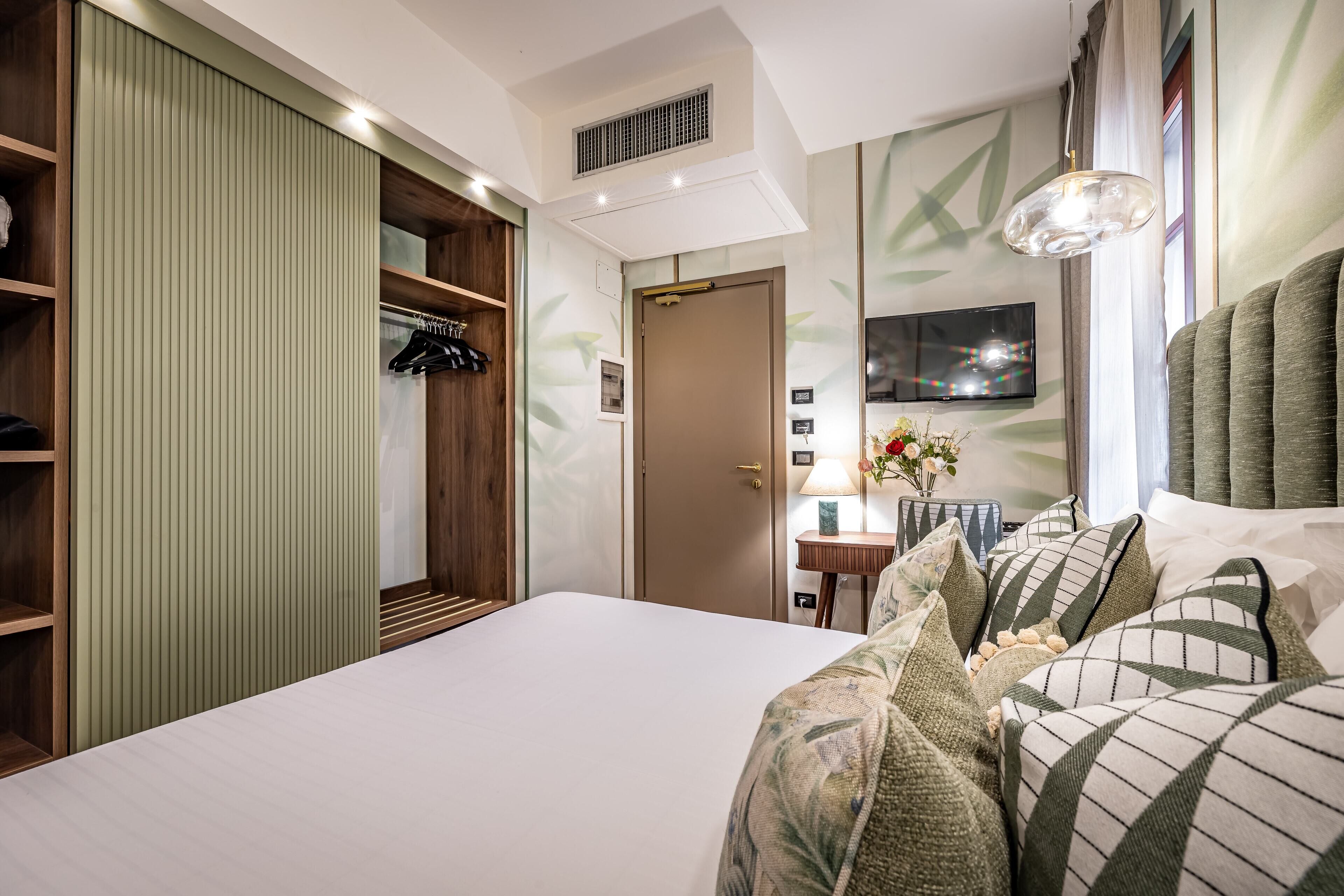 A hotel room with a large bed, a wardrobe, a television, and a lamp.