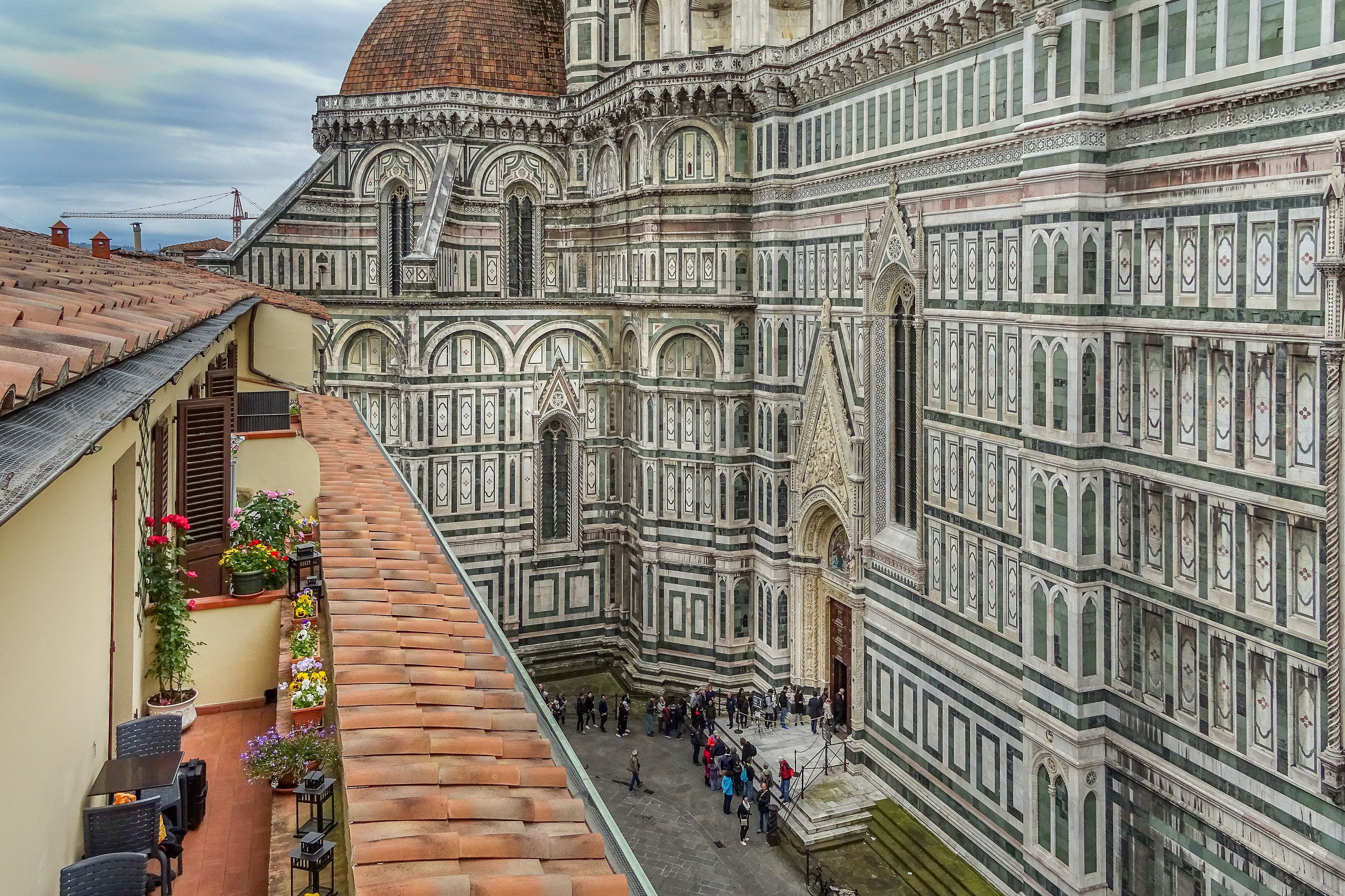 A view of the Florence Cathedral's facade with tourists in the foreground.
