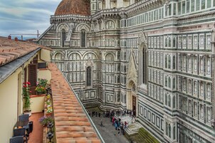A view of the Florence Cathedral's facade with tourists in the foreground.