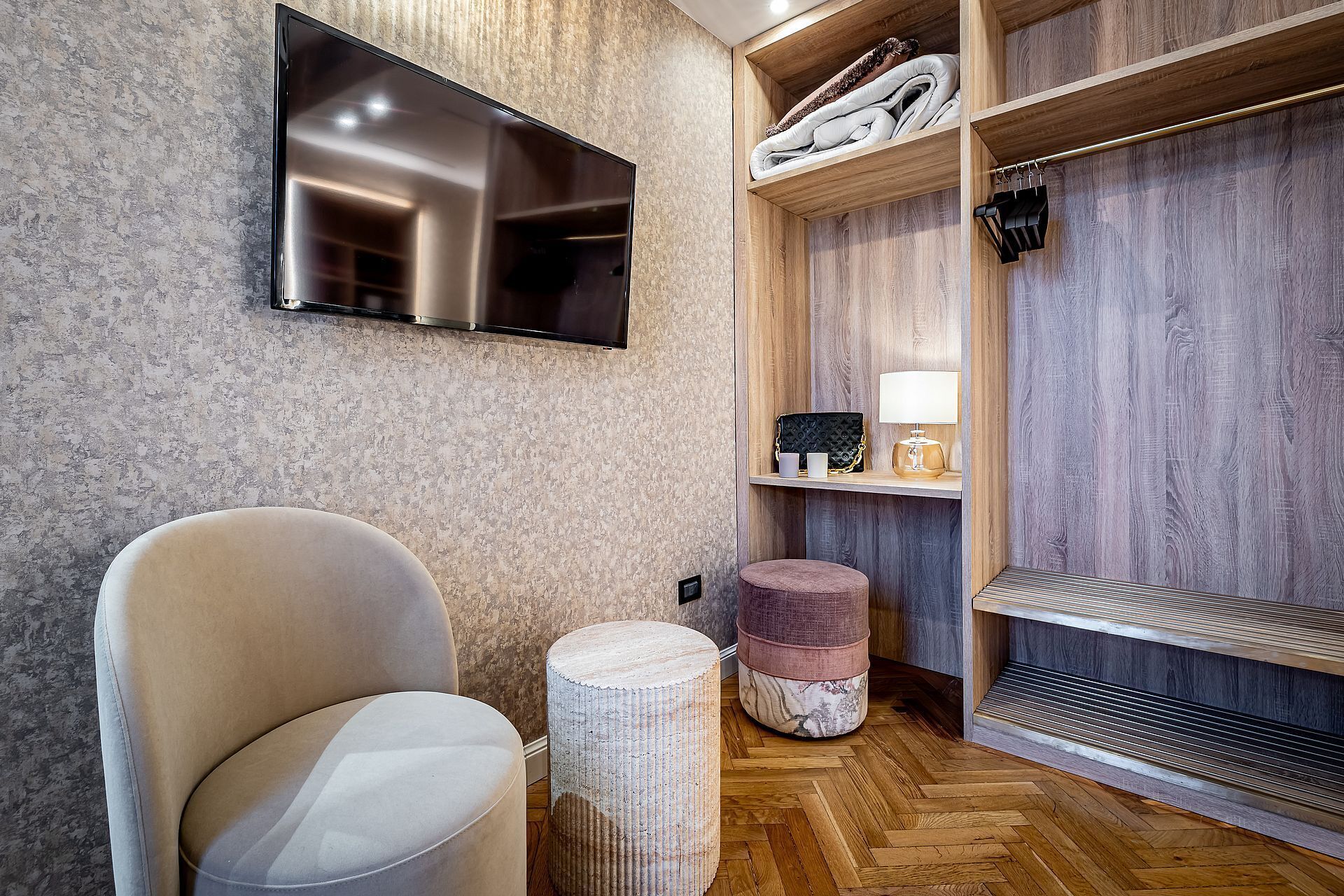 A modern bathroom with a large mirror, a flat-screen TV, a wooden vanity with a towel rack, and a bench.
