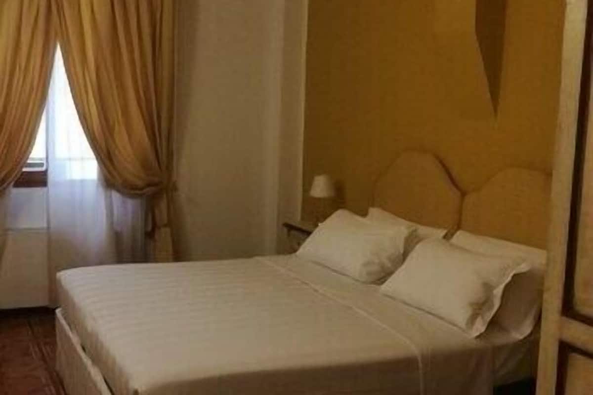 A bed in a room with a window and curtains.