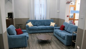 A modern living room with a blue sofa set, a coffee table, and a small side table. - Hotel Magenta (Florence)