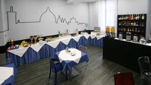 A dining area with tables set for a meal, a bar area with various beverages, and a wall with a city skyline silhouette. - Hotel Magenta (Florence)
