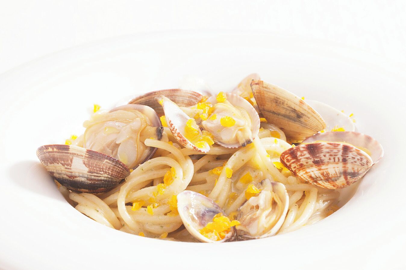 A bowl of pasta with clams and lemon zest.
