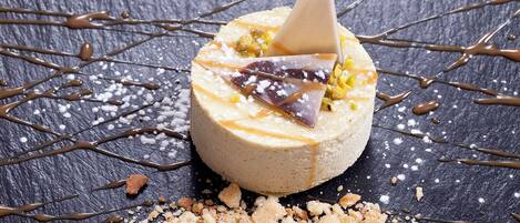 A dessert with a cone on top, drizzled with chocolate, and surrounded by crumbs and sugar on a dark surface.