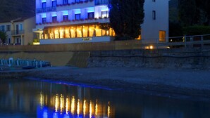 A modern hotel with a flat facade, multiple balconies, and a reflection in the water. - Baia d'Argento (Monte Argentario)