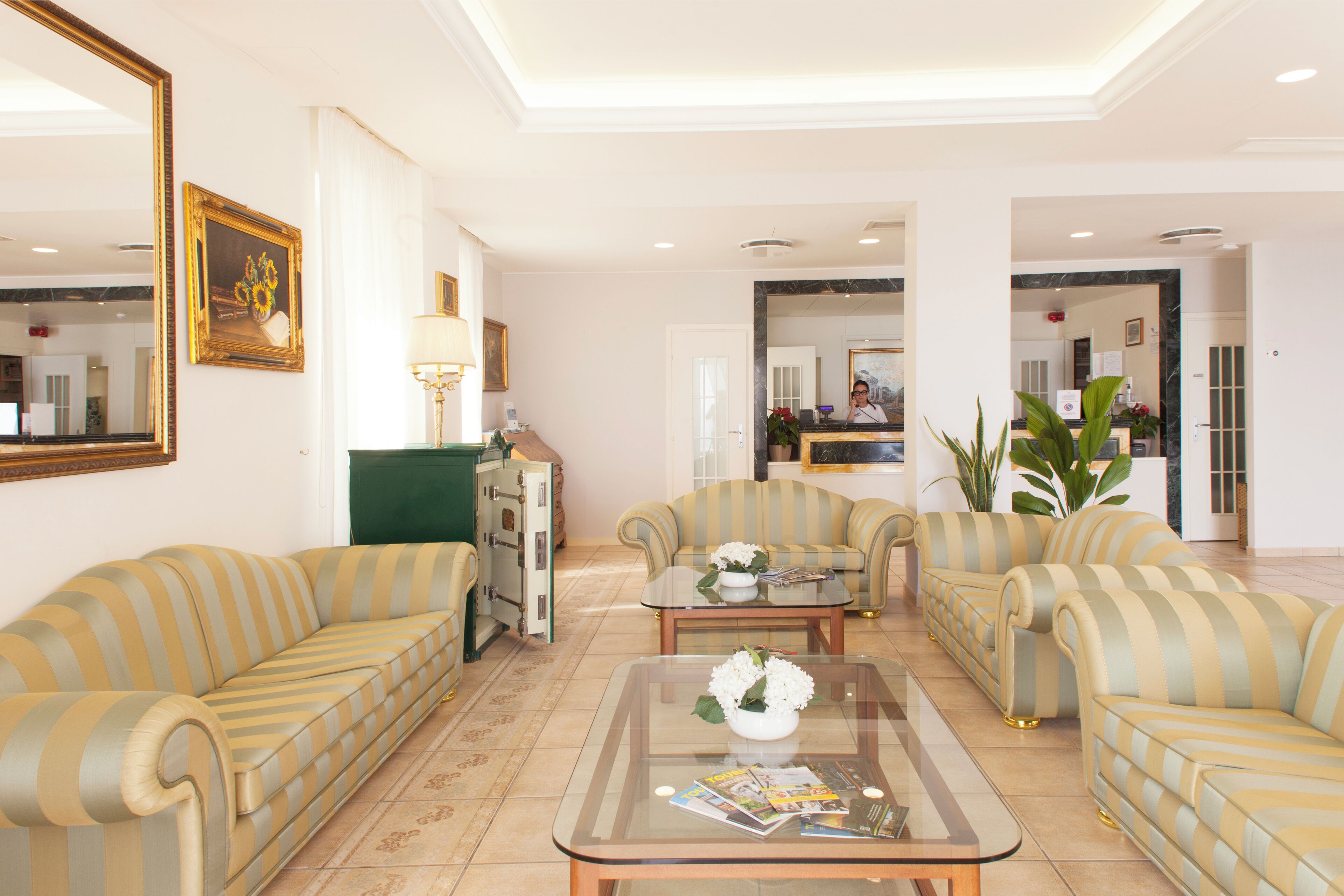 A spacious living area with striped sofas, a glass coffee table, and a green cabinet.