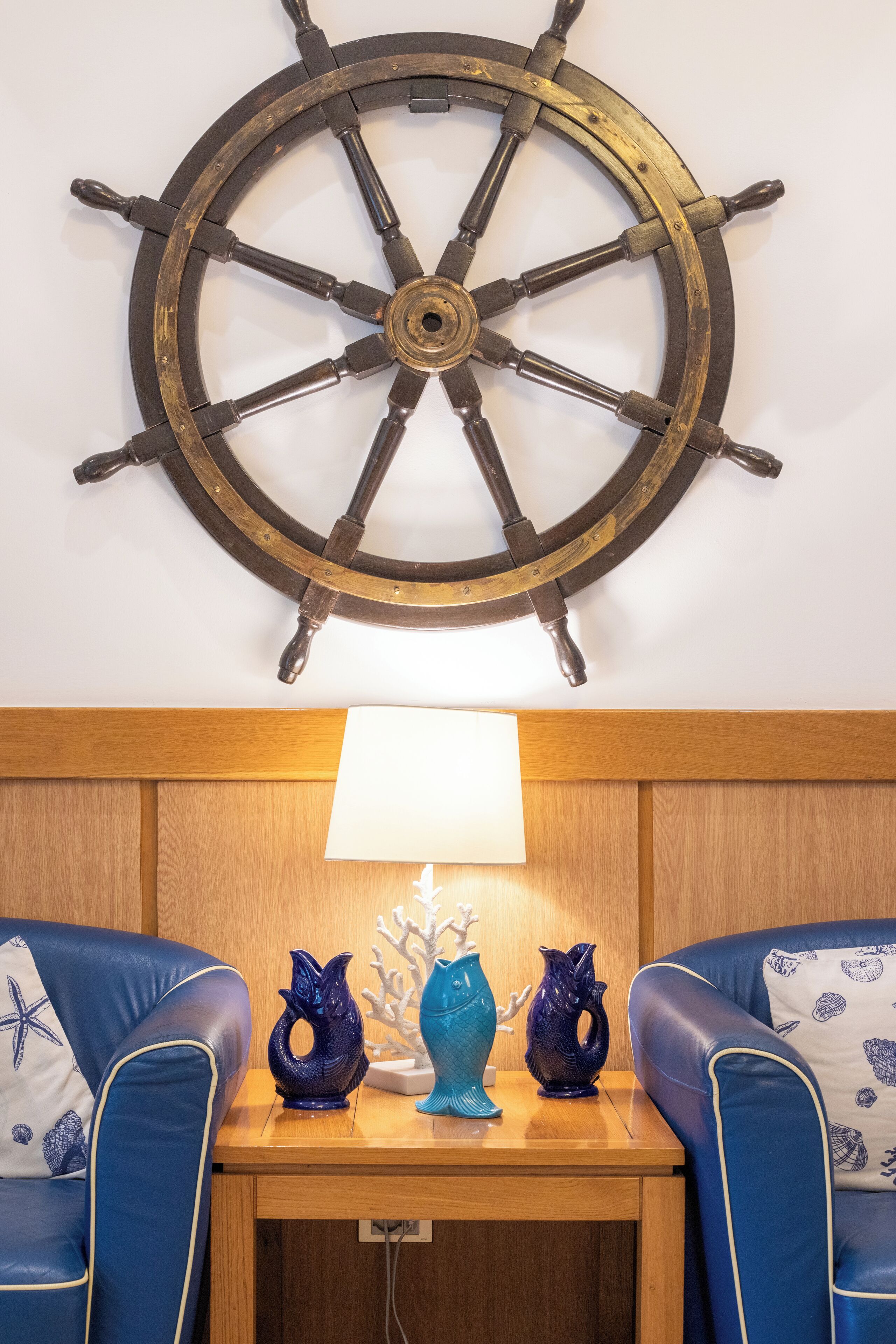 Une chambre avec une tête de lit en bois, une table ornée de vases décoratifs et un gouvernail de bateau fixé au mur.