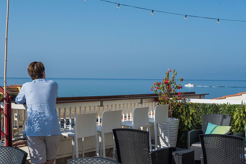 Eine Terrasse mit Sitzgelegenheiten im Freien mit Blick auf ein Gewässer.