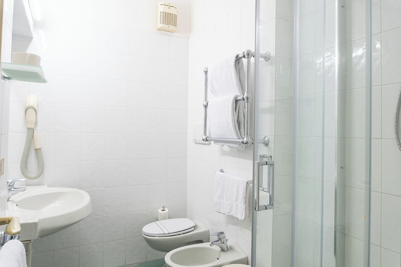 A modern bathroom with a glass shower enclosure, a sink, a toilet, and a towel rack.