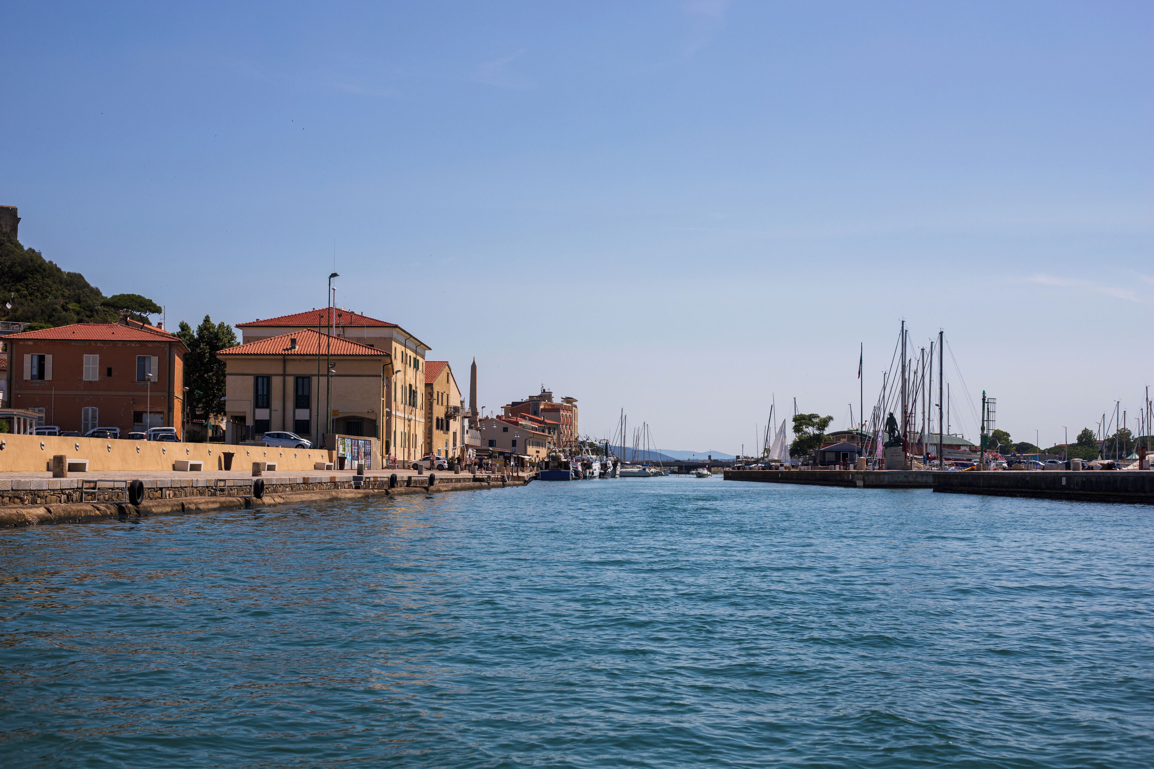 A waterfront area with buildings, a marina, and boats.