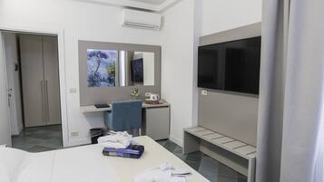 Une chambre d’hôtel avec un lit, un bureau et une chaise, une télévision et une salle de bain visible à travers une porte ouverte.
