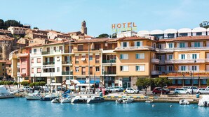 Un pueblo costero con un hotel destacado llamado "HOTEL CAPPRODO" y un puerto deportivo con barcos.